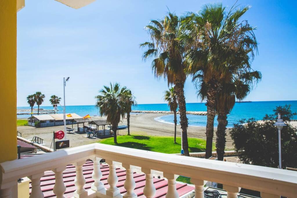 a balcony with a view of the beach and palm trees at Apartamento con vistas al mar en Pedregalejo playa in Málaga