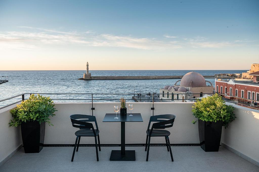 einen Tisch und Stühle auf einem Balkon mit Meerblick in der Unterkunft Anassa Chania Boutique Hotel in Chania