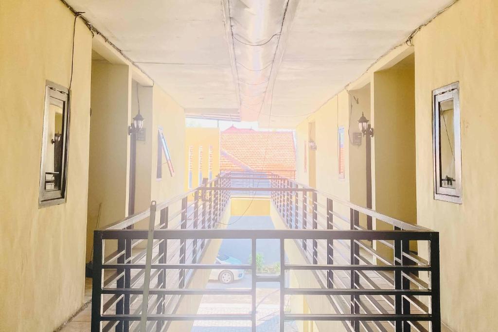 a hallway with a metal staircase in a building at Kanca Homestay Mitra RedDoorz near GOR Untung Suropati in Krampijangan