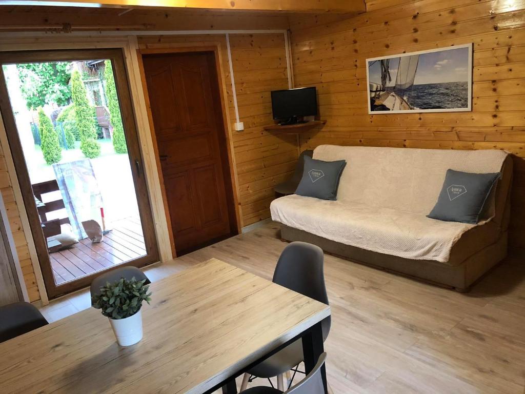 Pokój z kanapą, stołem i telewizorem w obiekcie Domki letniskowe Ibiza w Dźwirzynie