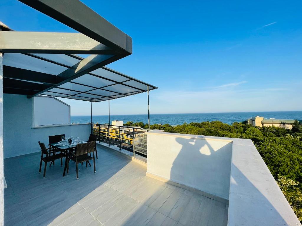 a dining table on a balcony with the ocean in the background at Sea Тerrace Aquamarine in Golden Sands