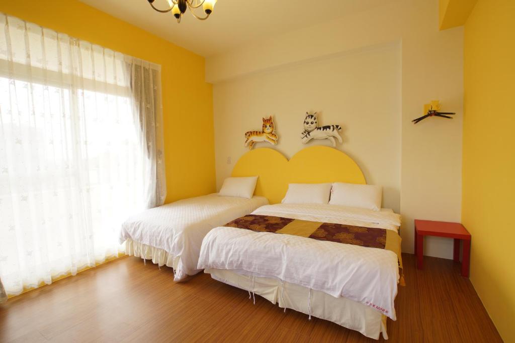 two beds in a room with yellow walls at 貓咪民宿Mini館-中午即可入房 in Taitung City