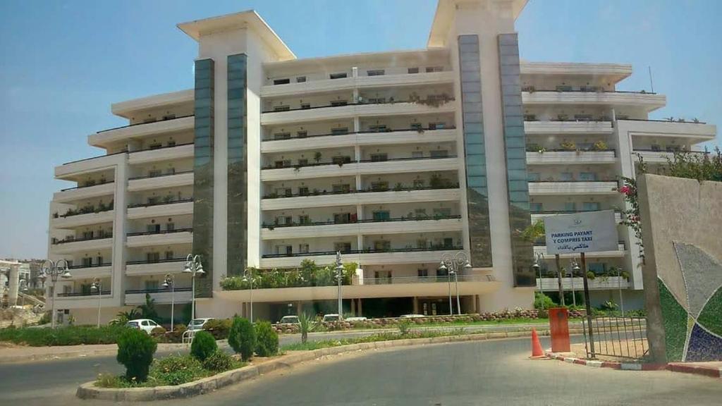 Marina Agadir appartement standing 90m2 + piscine في أغادير: عمارة سكنية كبيرة وامامها موقف للسيارات