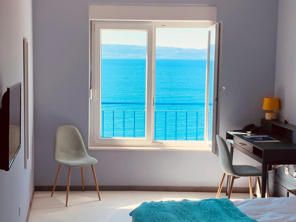 a bedroom with a window with a view of the ocean at Hotel Elu Iris in Split