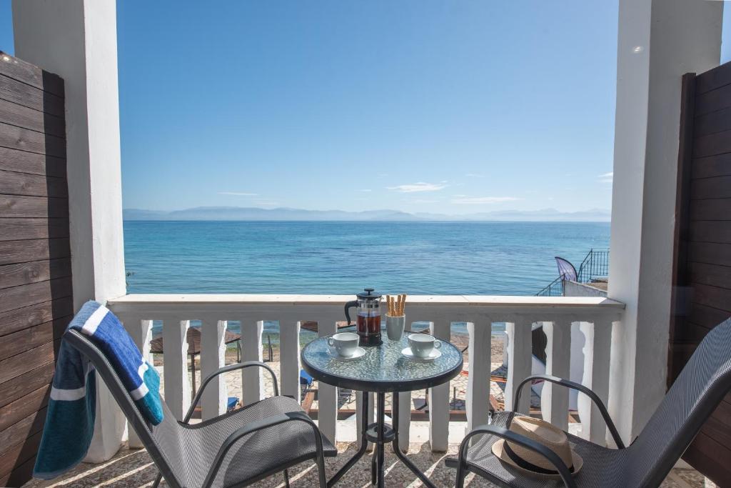 a table and chairs on a balcony with the ocean at Galini Beach Studios and Penthouse in Mesongi