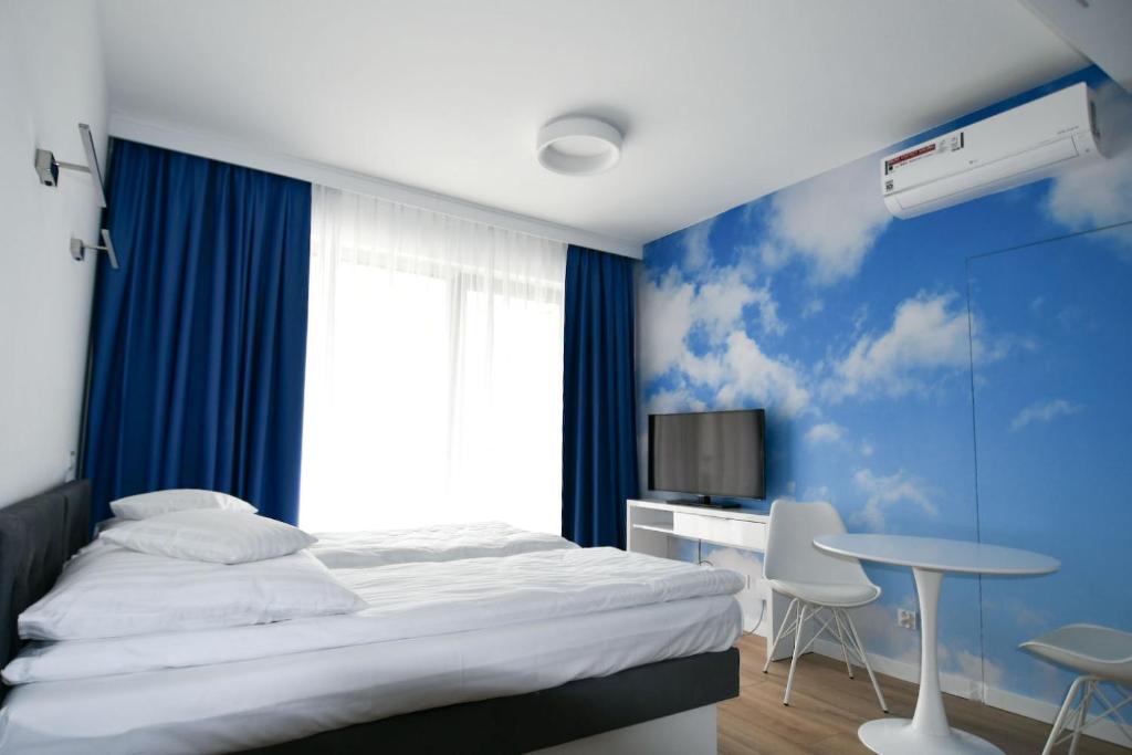 Schlafzimmer mit einem Bett, einem Schreibtisch und einem TV in der Unterkunft Blue Sky Apartments Rezydencja Niechorze - 301 in Niechorze