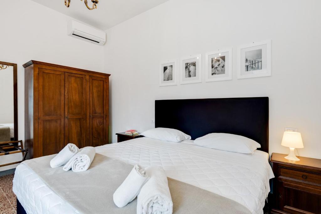 een slaapkamer met een groot wit bed met witte kussens bij The Country in the City - Parco delle Cascine Apartments in Florence