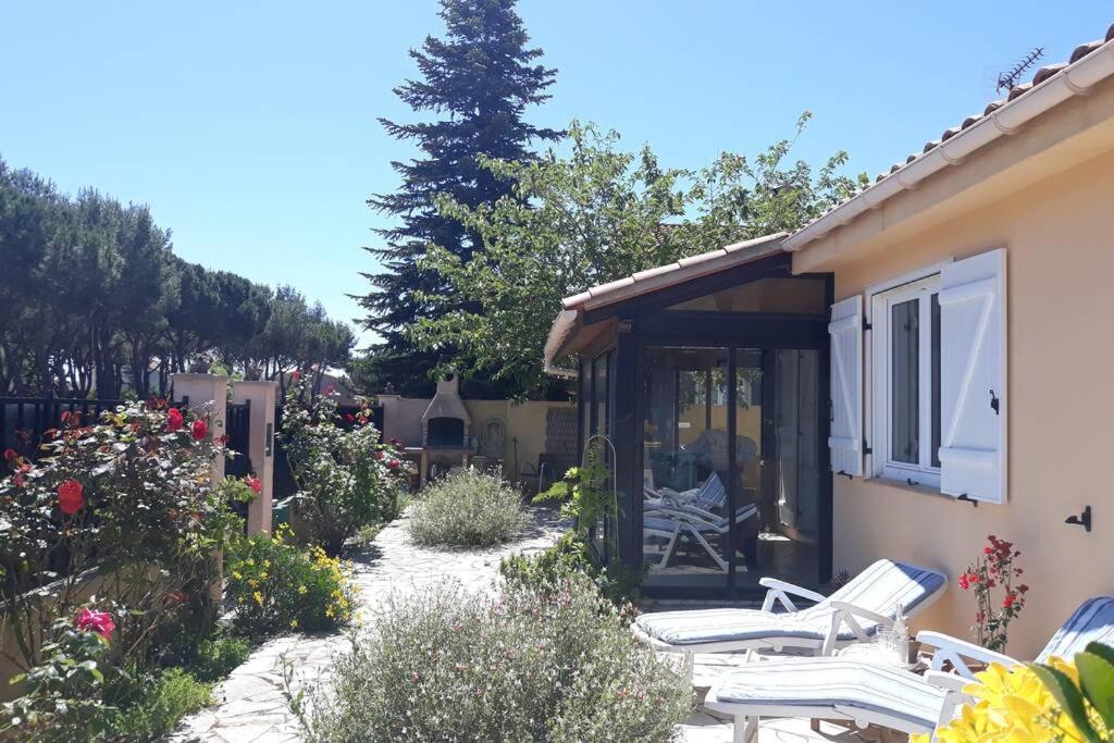 einen Garten mit weißen Stühlen und ein Haus in der Unterkunft Villa 3 étoiles près des plages, Parking, Wifi, Clim in Sauvian