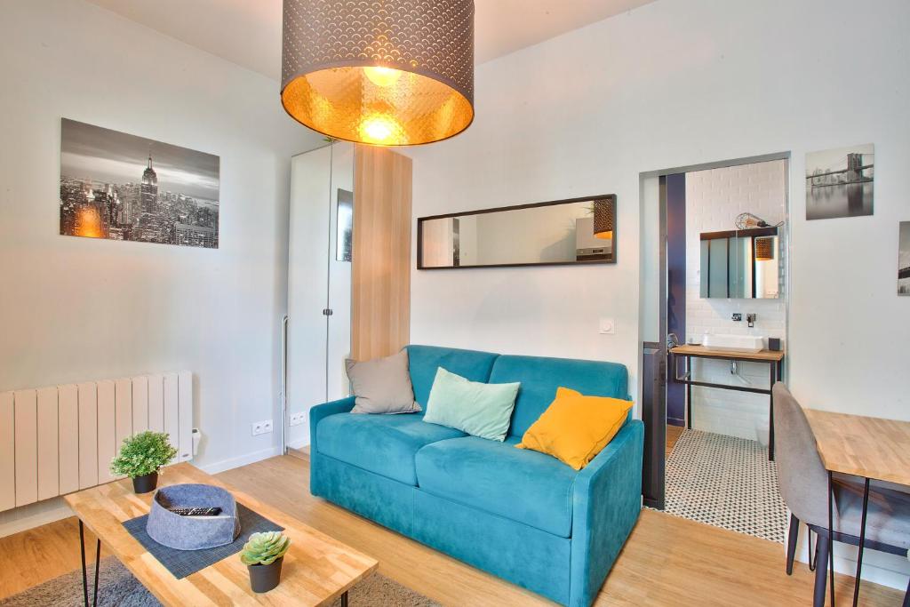 een woonkamer met een blauwe bank en een tafel bij CMG - Rouen Rive Droite - Gare in Rouen