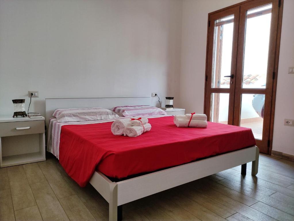 1 dormitorio con 1 cama con sábanas rojas y toallas en Casa Vacanza Stella del Mare, en Cala Gonone