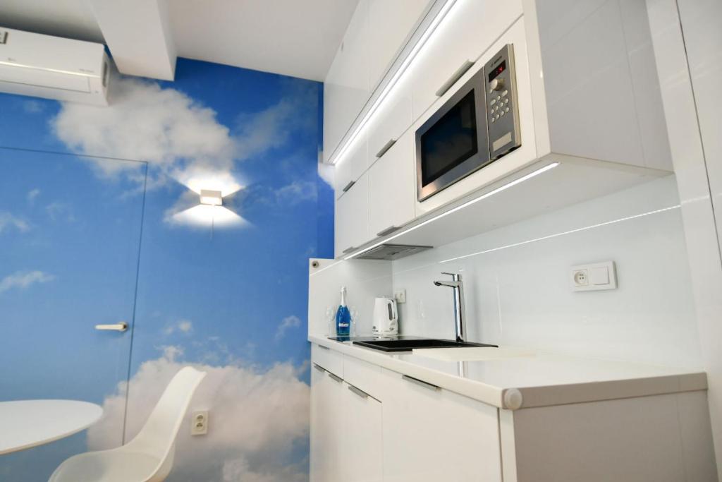 cocina con fregadero y microondas en Blue Sky Apartments Rezydencja Niechorze, en Niechorze