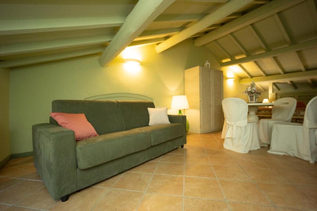 a living room with a green couch and white chairs at Vecchio Granaio in Pisa