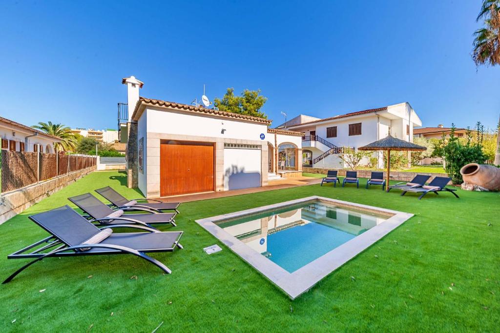 un patio con piscina, sillas y una casa en villa amfora, en Puerto de Alcudia