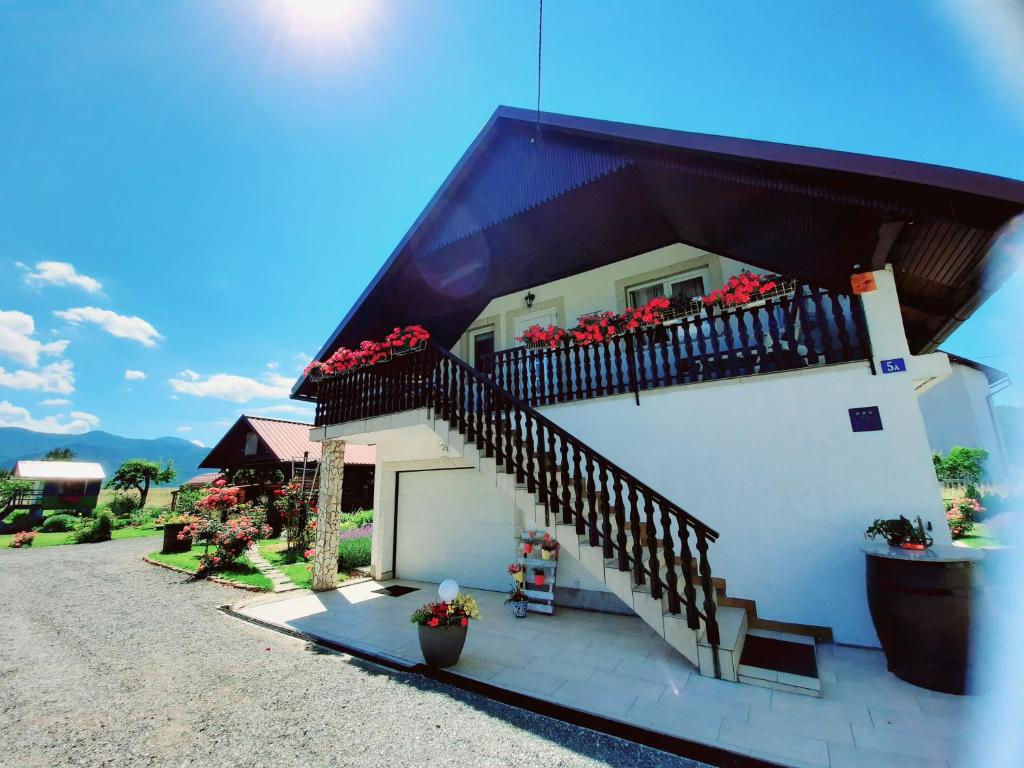 ein weißes Haus mit einem Balkon mit Blumen darauf in der Unterkunft Kuća za odmor Delak in Fužine