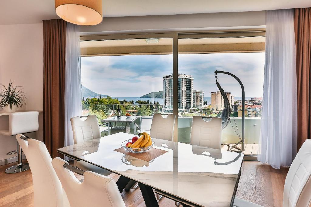 a dining room with a glass table and a large window at Lux Panorama in Budva