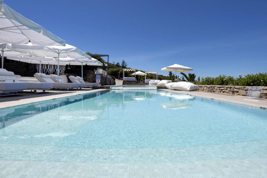 a large swimming pool with white chairs and umbrellas at Paros Butterfly Villas in Pounda