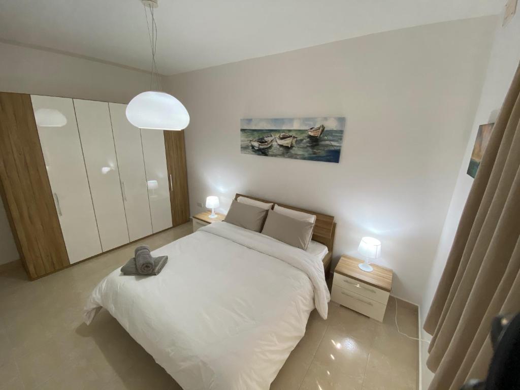 sypialnia z białym łóżkiem i 2 szafkami nocnymi w obiekcie Rock Bay w mieście Birżebbuġa