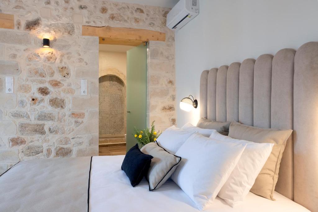sypialnia z białym łóżkiem i kamienną ścianą w obiekcie CASA GIORGIO EXCLUSIVE SUITES w Retimnie