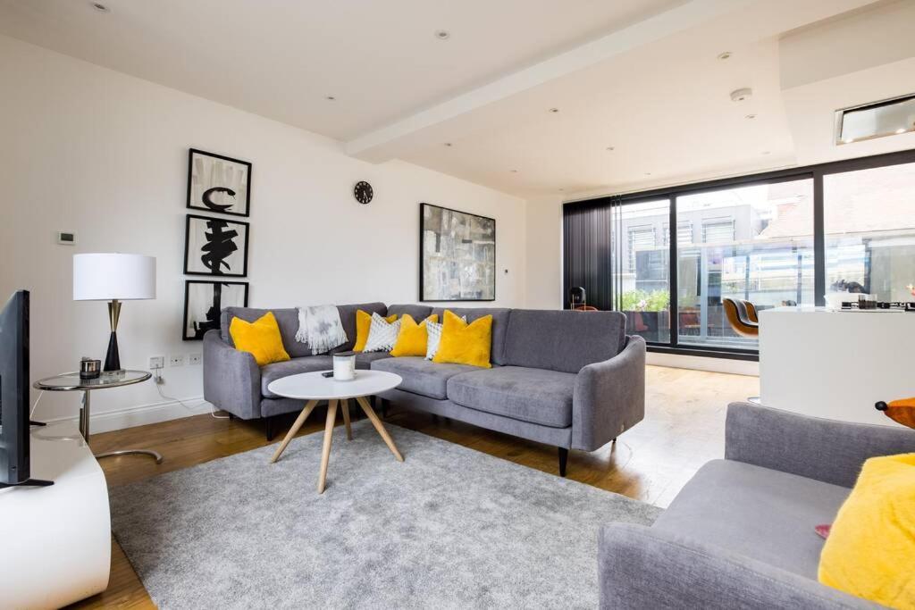 sala de estar con sofá gris y almohadas amarillas en Discounted Spacious 3bedroom By King Cross Camden, en Londres