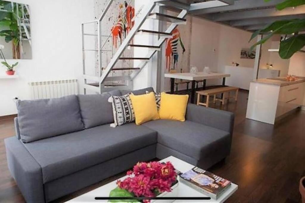 a living room with a gray couch with yellow pillows at LUJOSO LOFT a 2min a pie del casco histórico in Seville