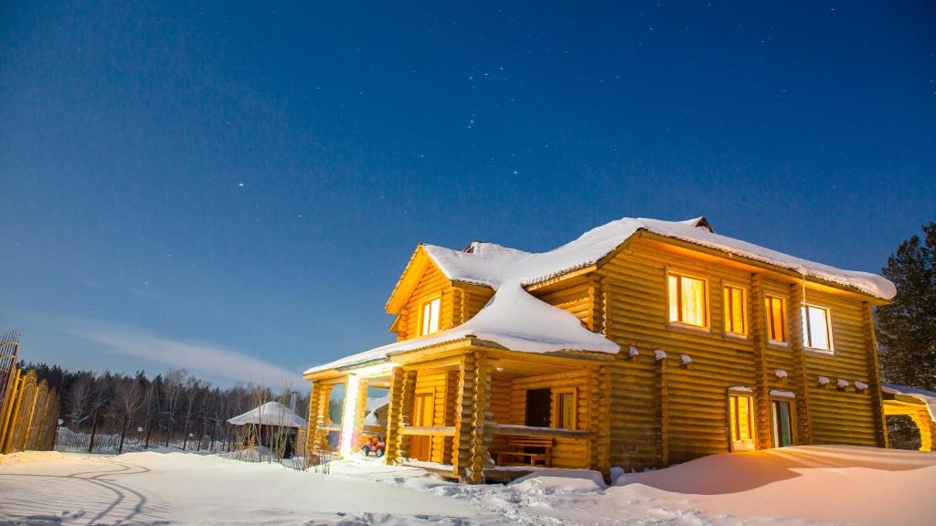 a wooden house with snow on top of it at Земляничная поляна Боровое in Shchuchinskiy