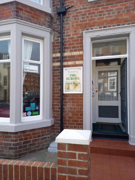 un edificio de ladrillo con un cartel en la ventana de una tienda en The Europa, en Whitby