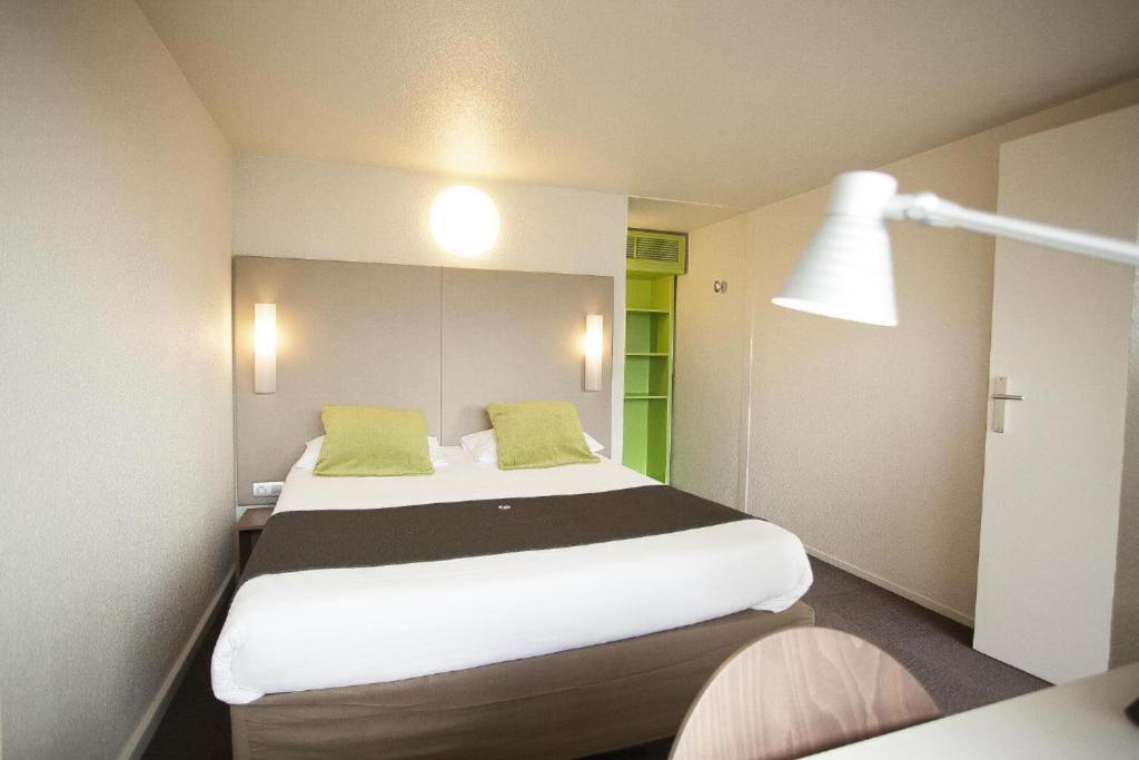 ブラザックにあるAmpaline HOTEL - Perigueux Boulazacのベッドルーム(緑の枕が付く大きな白いベッド付)