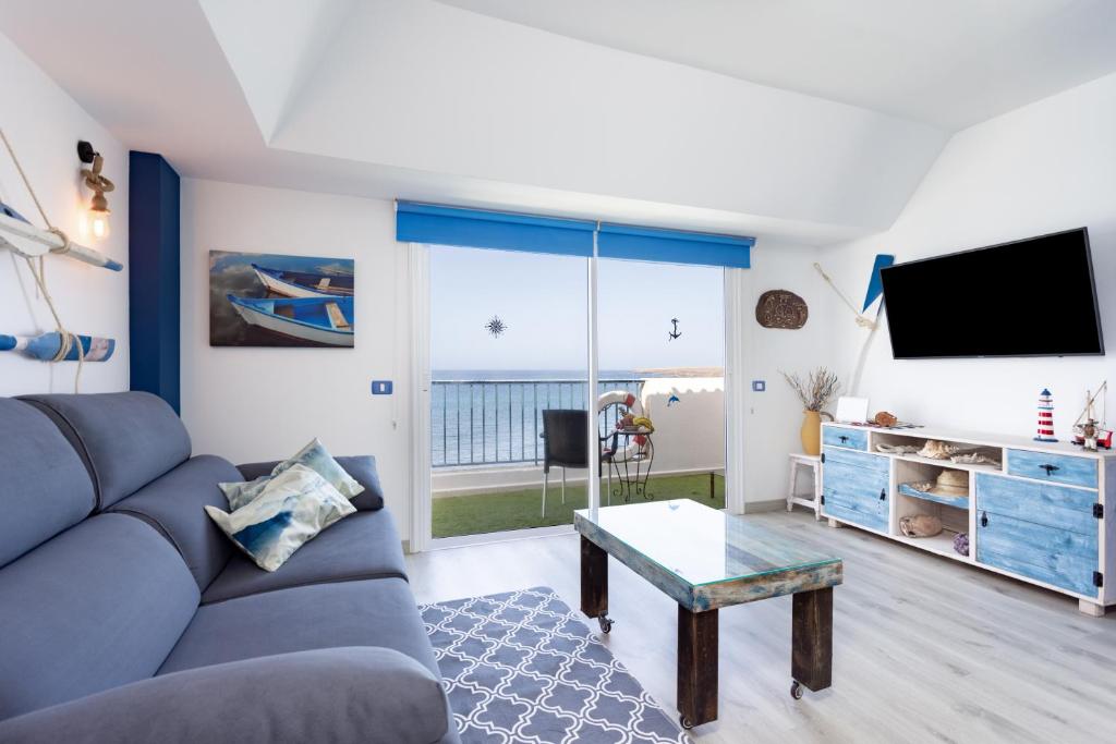 ein Wohnzimmer mit einem Sofa und einem TV in der Unterkunft Home2Book Sea Front Attic Las Galletas in Las Galletas