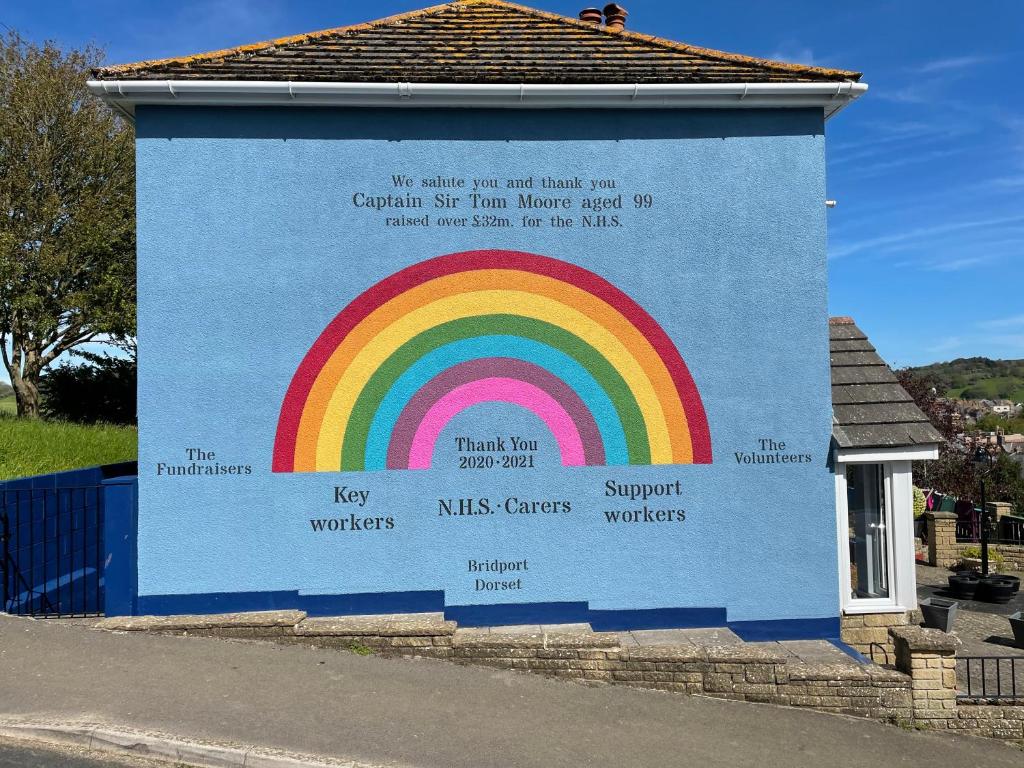 un mural de un arco iris en el lateral de un edificio en Southcroft, en Bridport