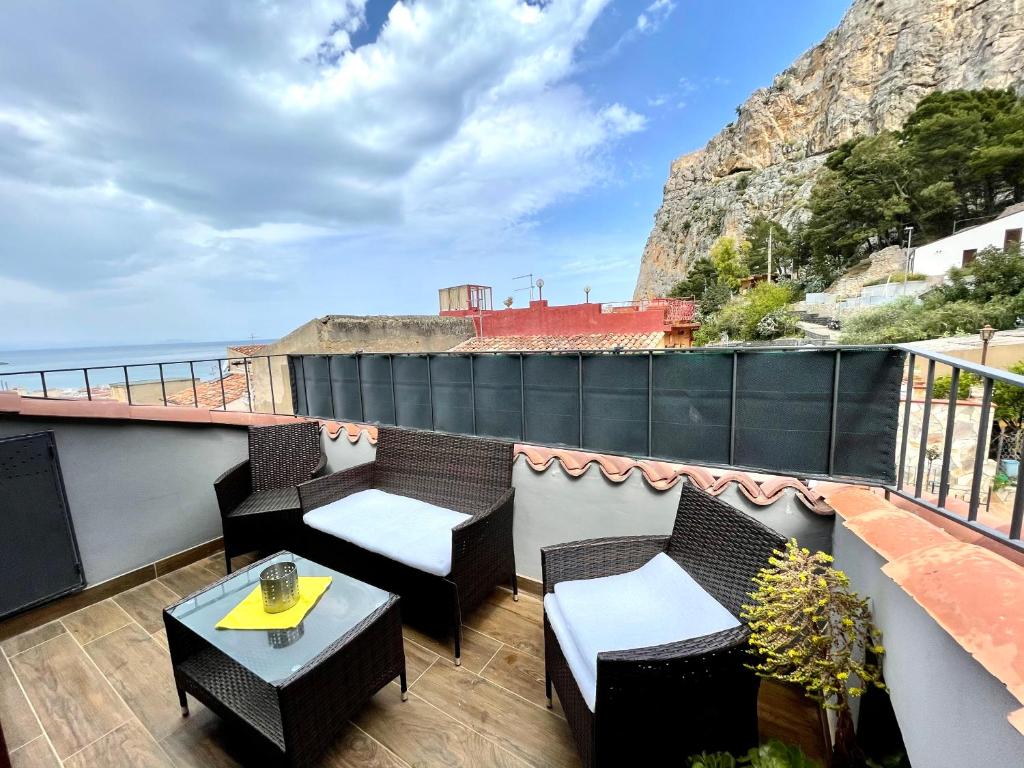 einen Balkon mit Tischen und Stühlen und Meerblick in der Unterkunft Casa le Maioliche by Housilia in Cefalú