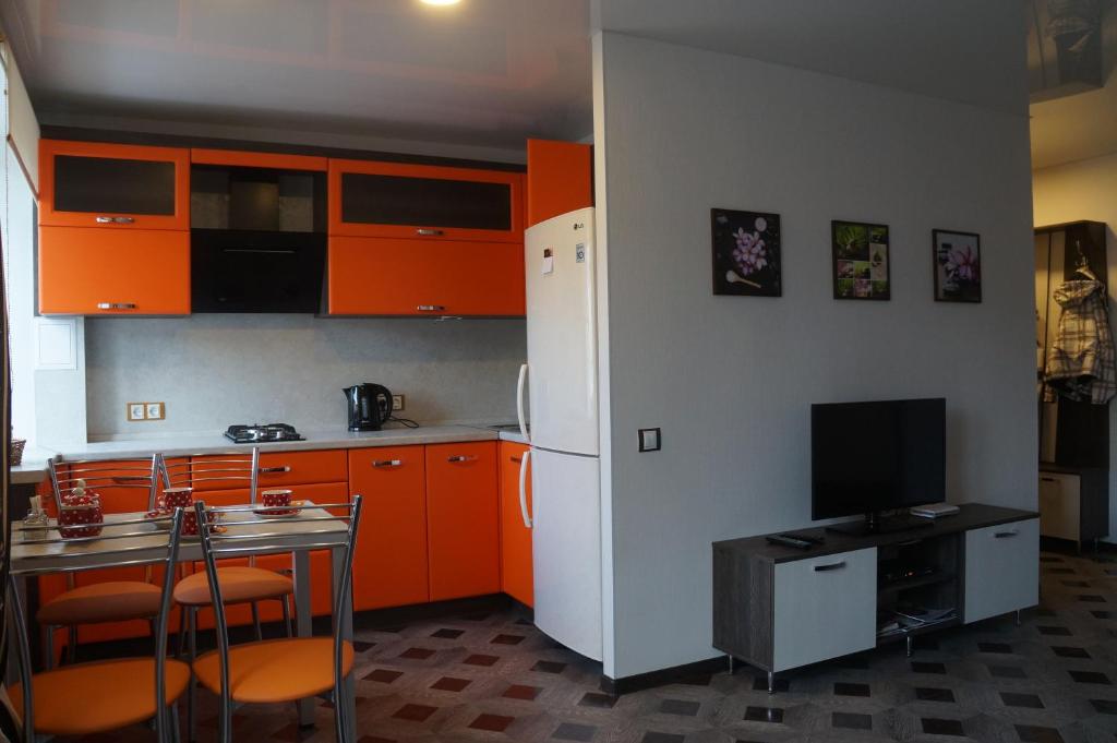 ペトロザヴォーツクにあるOnegohomeのキッチン(オレンジ色のキャビネット、白い冷蔵庫付)