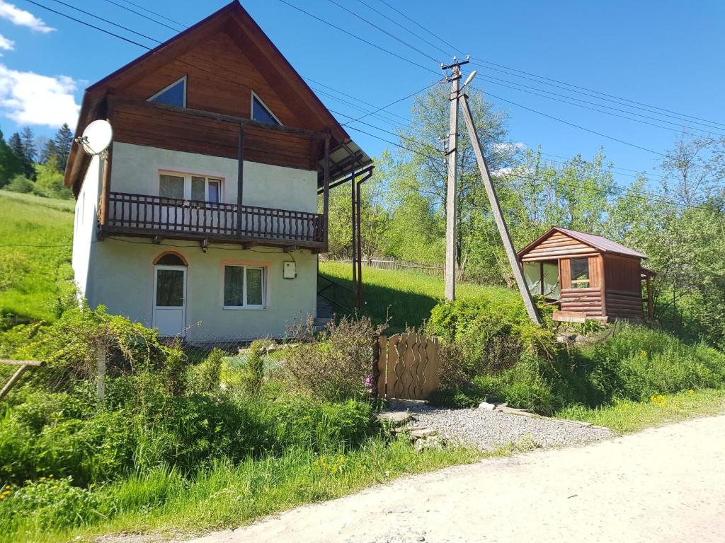 a small house with a balcony on the side of a road at Карпатський будинок in Izki