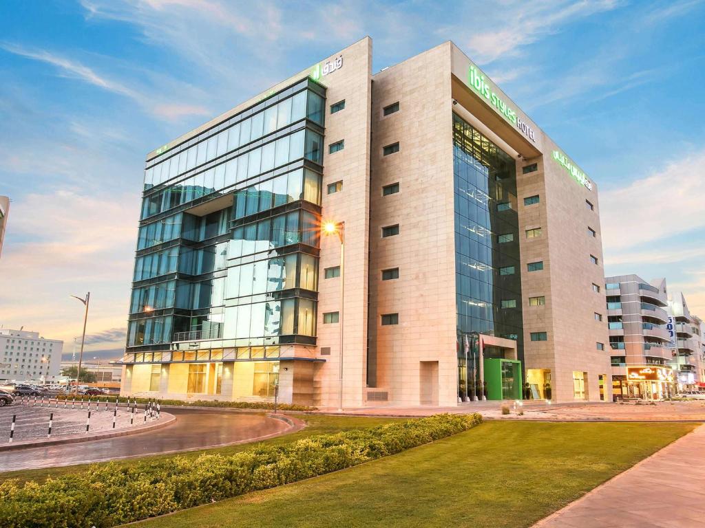a large building with glass windows in a city at Ibis Styles Dubai Jumeira in Dubai
