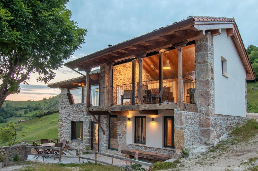 una casa en una colina con una cubierta alrededor en Pulieru - Picos de Europa views, designed for all seasons, en Cangas de Onís