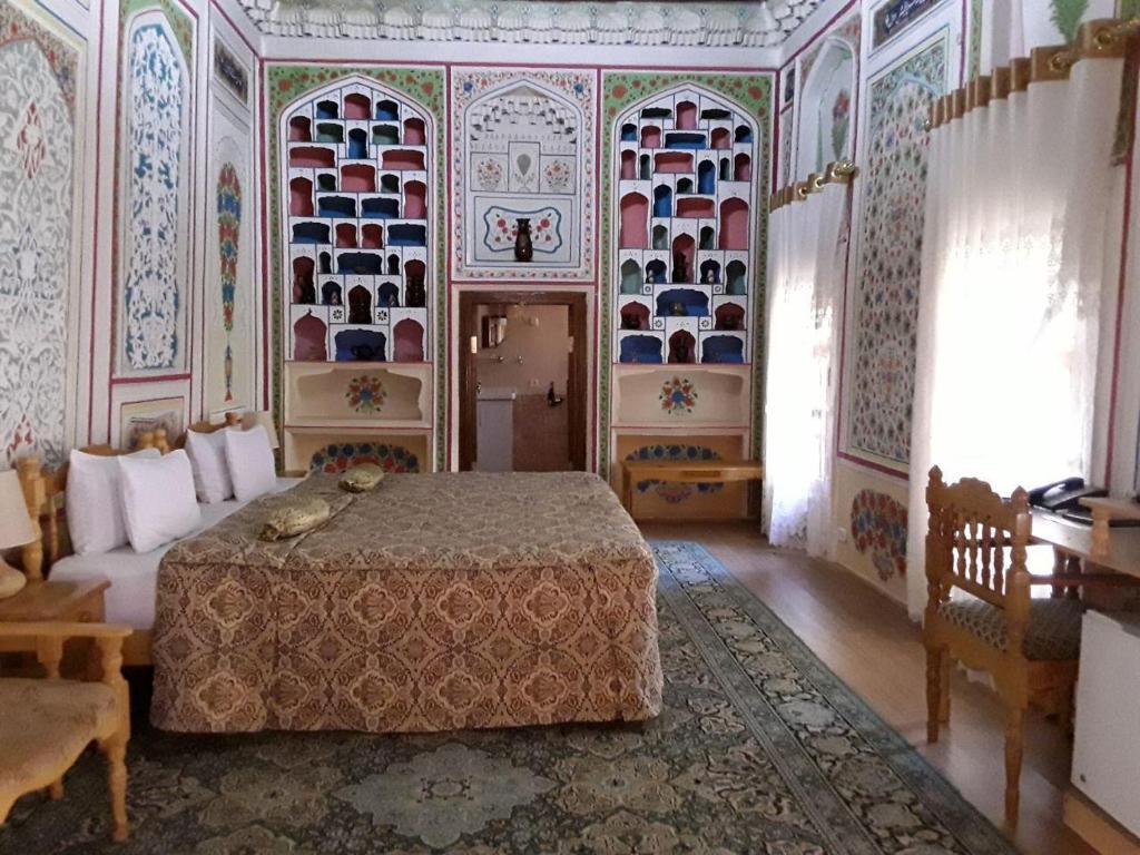 a bedroom with a bed in a room with colorful walls at Sasha & Son Hotel in Bukhara