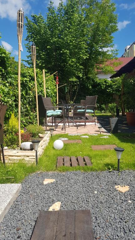 un jardín con bancos, mesa y sillas en Joy Guesthouse, en Siófok