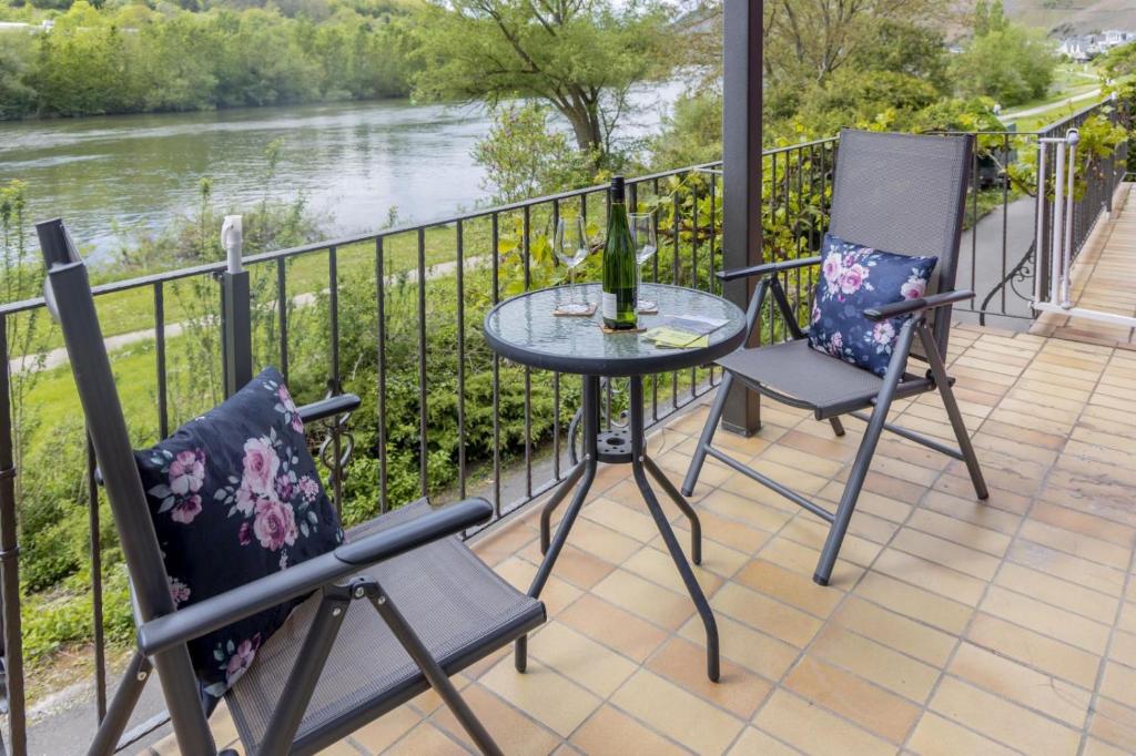 two chairs and a table on a balcony with a river at Ferienhaus Moselherz in Merl