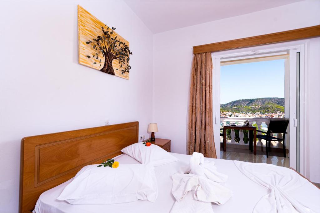 a bedroom with a bed with white sheets and a window at Poros View in Galatas