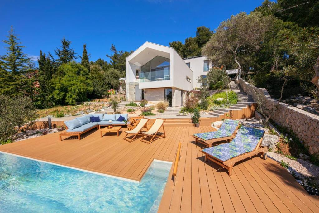 Casa con terraza de madera con sillas y piscina en Villa del Mar, en Mali Lošinj
