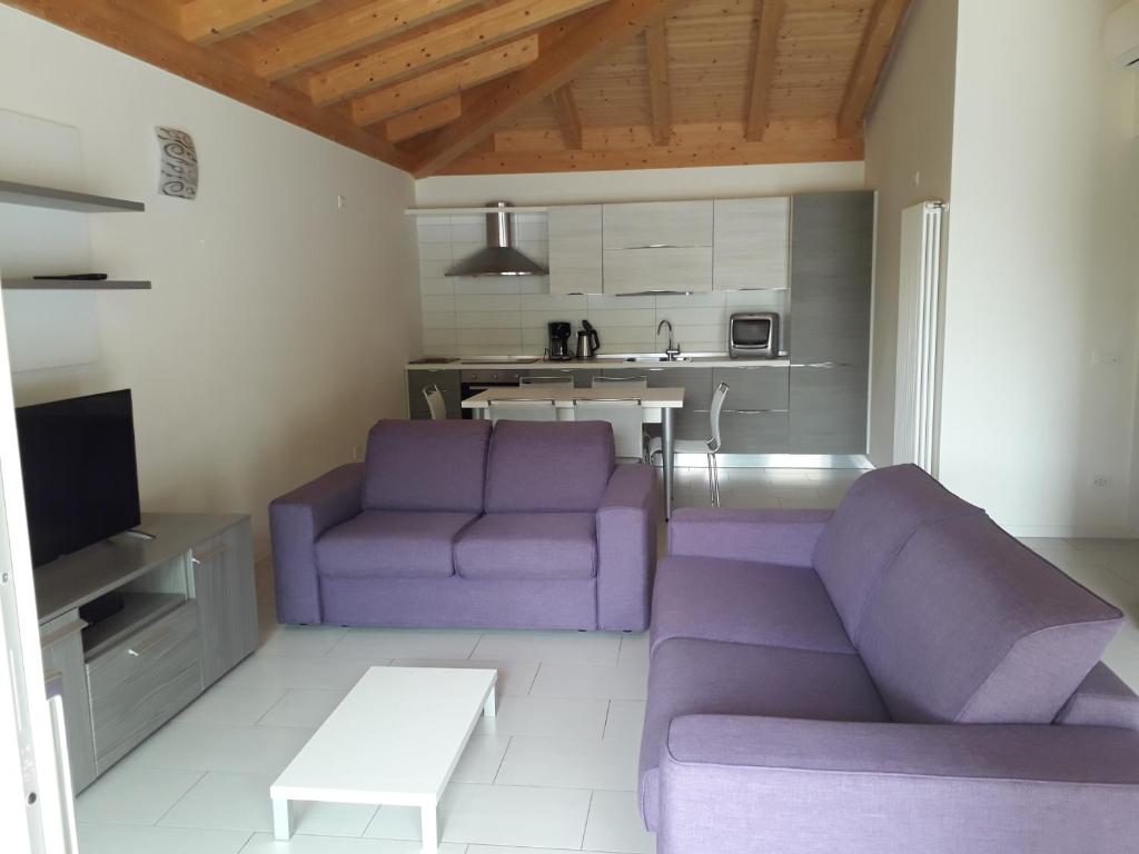 uma sala de estar com sofás roxos e uma cozinha em Appartamenti Magosta em Malcesine