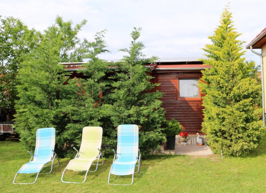 a group of chairs sitting in the grass in front of a cabin at Eszter Nyaralóház in Zánka