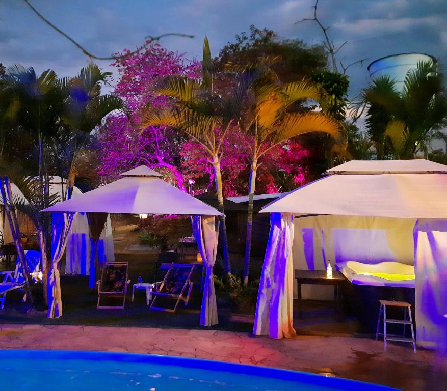 two umbrellas and a swimming pool at night at Pousada Confraria Casa Branca in Casa Branca