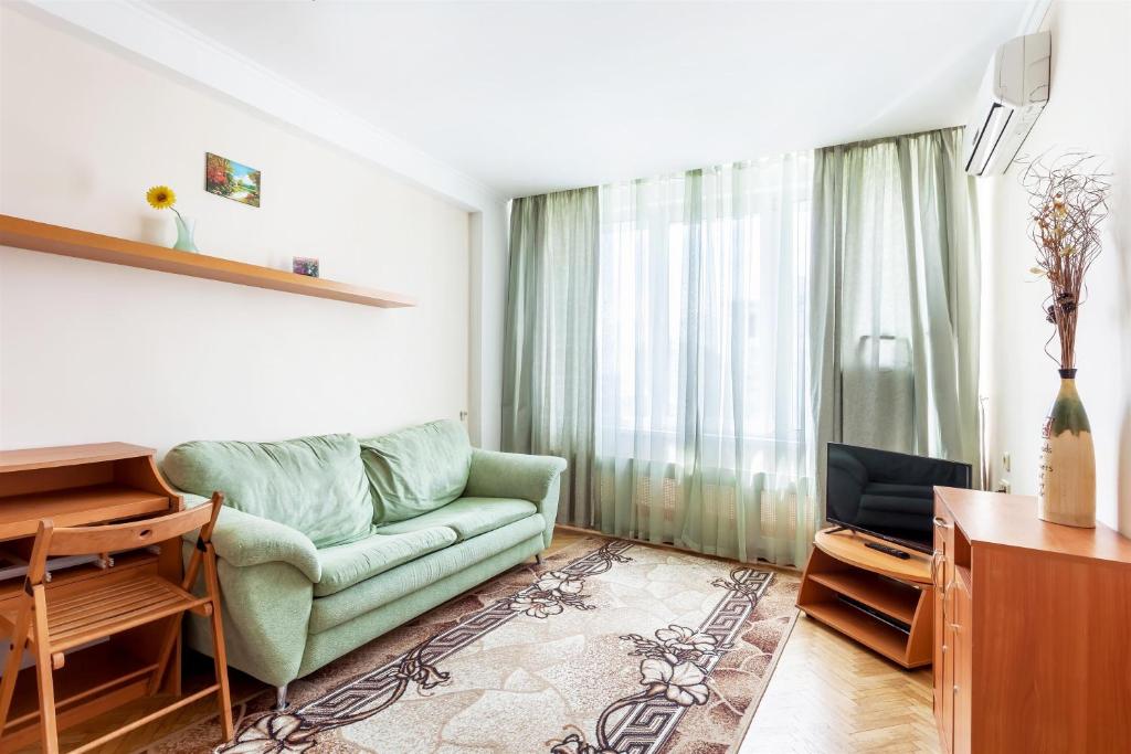 a living room with a green couch and a television at ApartLux Novoarbatskaya Superior 2 in Moscow