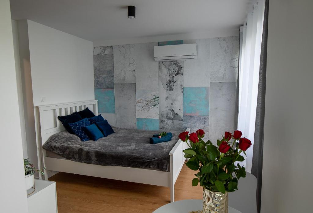a bedroom with a bed with a vase of red flowers at Apartament Kuba in Warsaw