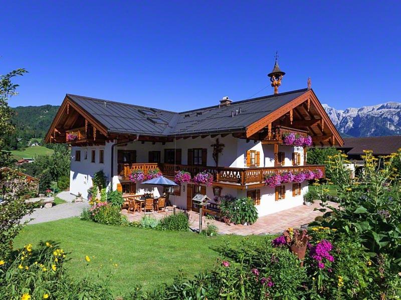 een groot wit huis met een veranda en een dak bij Hinterkeilhof in Bischofswiesen