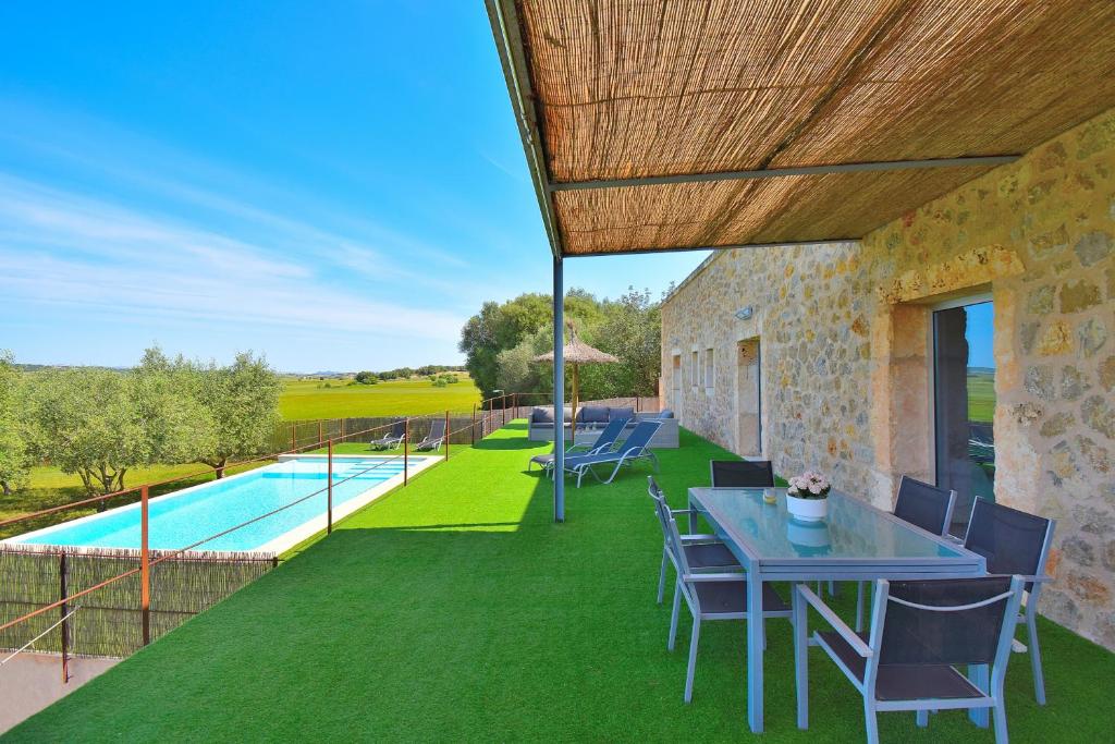 een patio met een tafel en stoelen en een zwembad bij Finca Es Gassons 012 by Mallorca Charme in Maria de la Salut