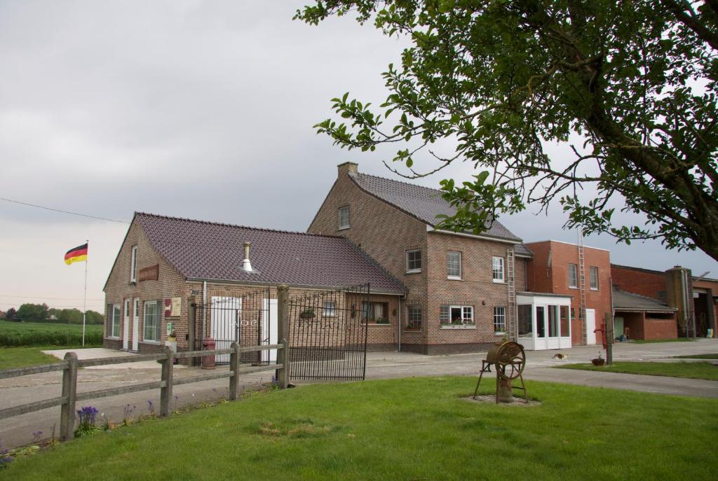 a house with a statue in the grass in front of it at Breeden Steeger Hoeve in Lichtervelde