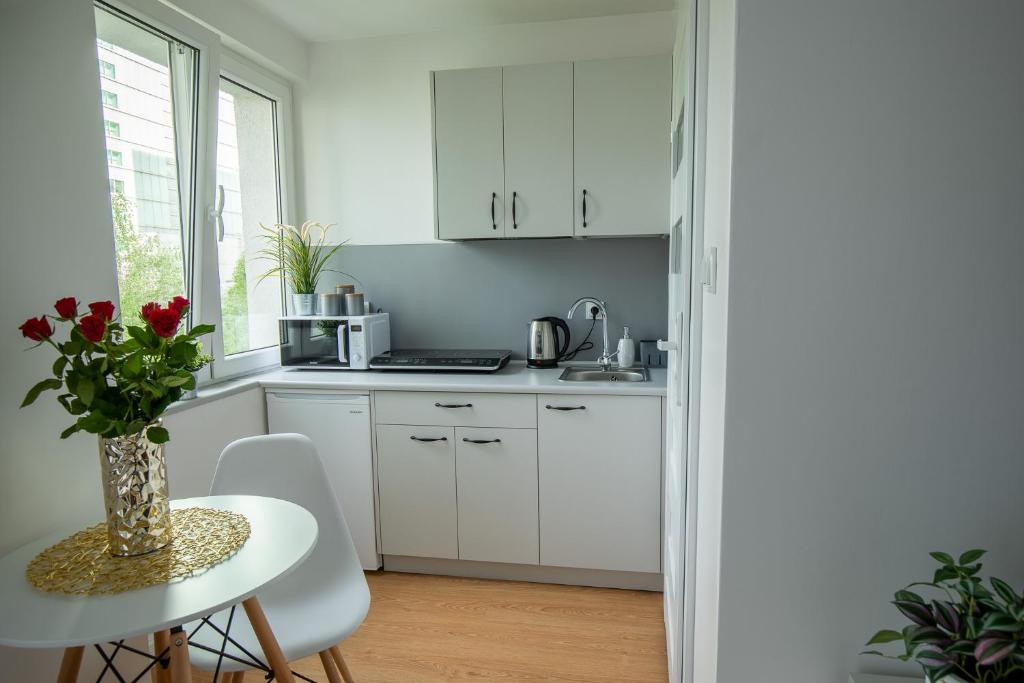 een keuken met witte kasten en een tafel met een vaas met bloemen bij Apartament Ola in Warschau