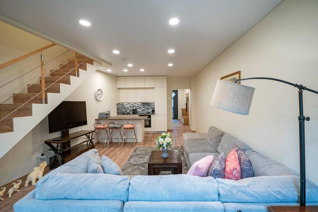 a living room with a blue couch and a staircase at Homely Krevės apartment by Polo Apartments in Kaunas