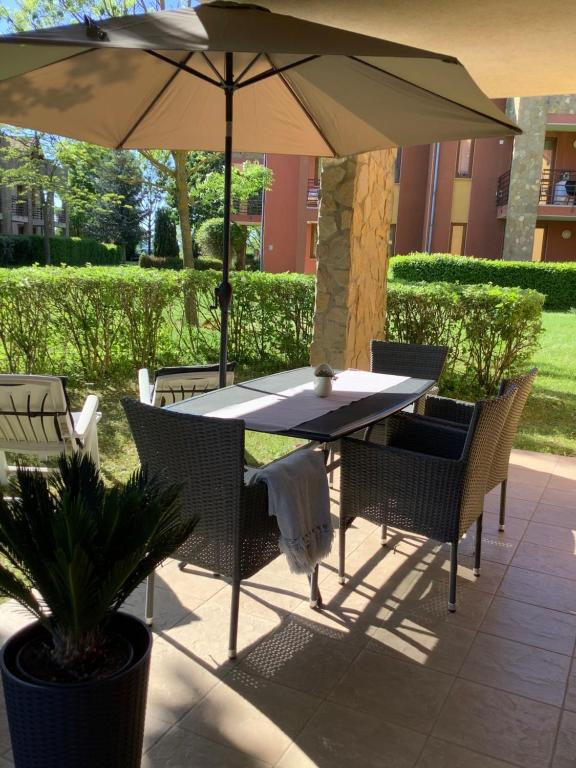 einen Tisch und Stühle unter einem Sonnenschirm auf einer Terrasse in der Unterkunft Apartman Golf Lux in Bük